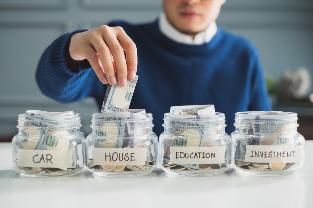 The man of hand by putting money on the jar for the future, the money plan, the money and the concept of management.